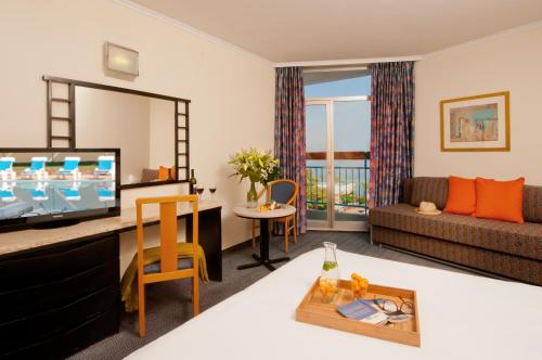 a living room with a television and a couch at Leonardo Club Tiberias - All Inclusive in Tiberias