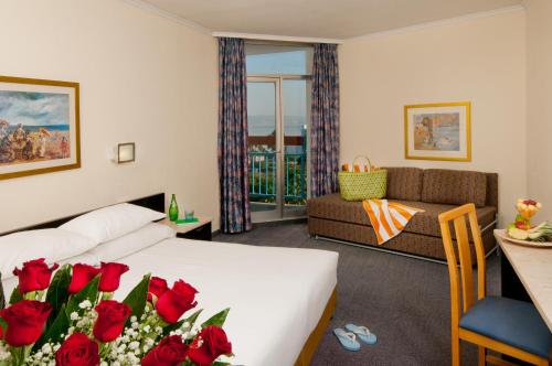 a hotel room with a bed and red roses at Leonardo Club Tiberias - All Inclusive in Tiberias