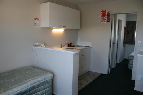 Habitación pequeña con cama y armario blanco en 88 Wallace Court Motel, en Wellington