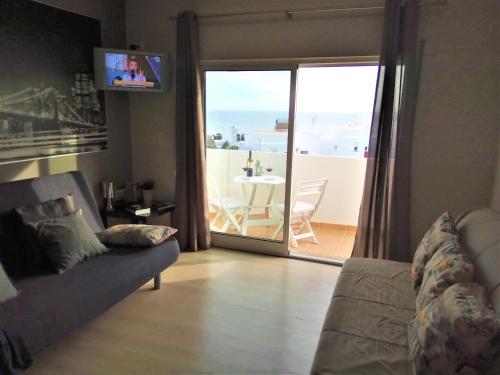 a living room with a couch and a view of a balcony at Apartamento de Praia - Albufeira in Albufeira
