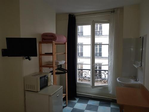 a bathroom with a television and a window with a balcony at Au Royal Mad in Paris