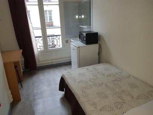 Habitación pequeña con cama y nevera. en Au Royal Mad, en París