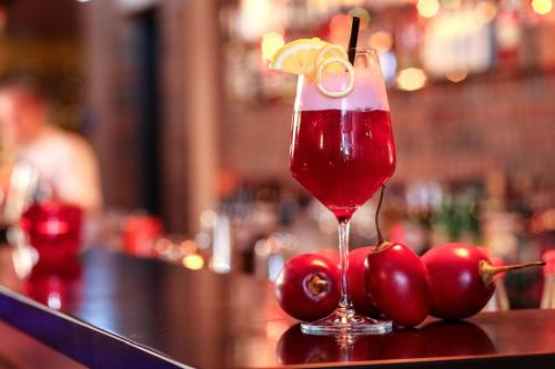 a drink sitting on top of a bar with red cherries at Altes Stahlwerk Business & Lifestyle Hotel in Neumünster