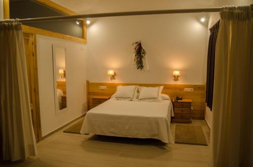 a bedroom with a white bed and a mirror at Hotel Las Casitas in Boceguillas