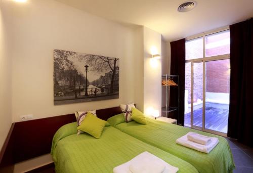 a bedroom with a green bed and a window at Reino de Valencia Apartments in Valencia