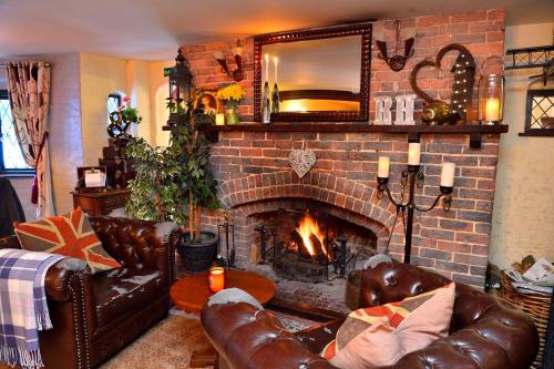 a living room with a brick fireplace and leather couches at The Roundabout Hotel in Pulborough