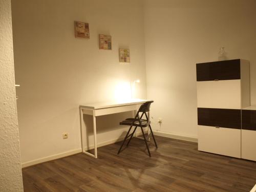 a desk in a room with a chair and a refrigerator at Appartment Grau im Grünen in Mönchengladbach