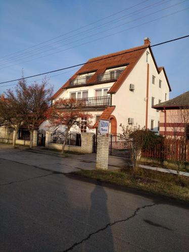 a large white house with a fence in front of it at Szilvia Panzió Gyomaendrőd in Gyomaendrőd