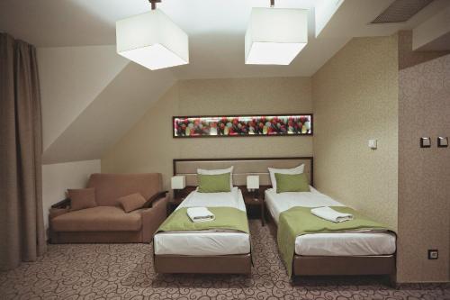 a hotel room with two beds and a couch at Hotel Janów in Janów Lubelski