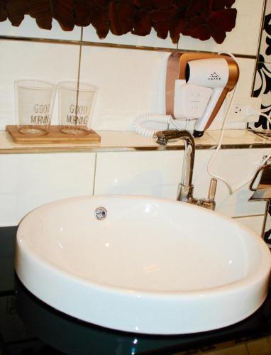 a bathroom sink with a hair dryer and two glasses at Home & Teak Homestay in Jinning
