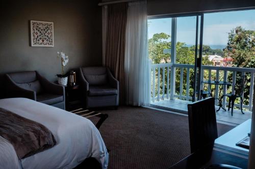 a hotel room with a bed and a balcony at Cinnamon Boutique Guest House in Wilderness