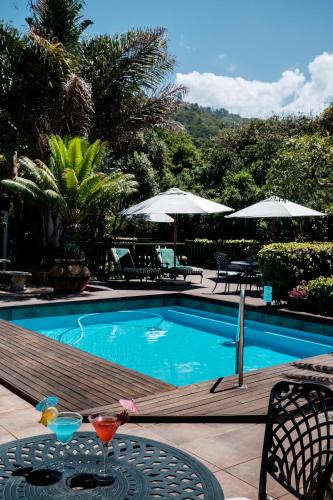 a swimming pool with a drink on a wooden deck at Cinnamon Boutique Guest House in Wilderness