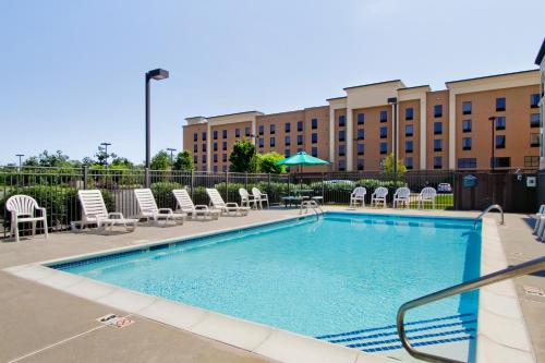 a swimming pool with chairs and a building in the background at Wingate by Wyndham Vineland in Vineland