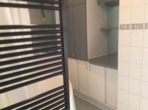 a kitchen with white cabinets and a black rack at James D in De Haan