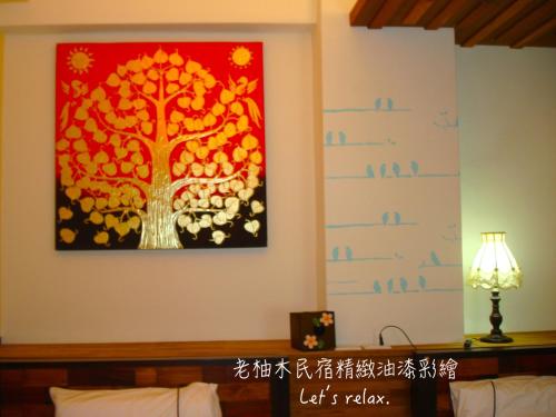 a painting of a tree on the wall of a room at Home & Teak Homestay in Jinning