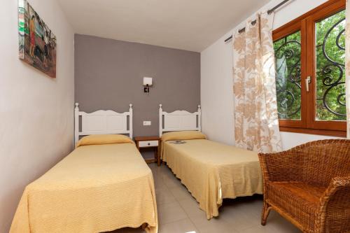 ポルト・ダ・ポリェンサにあるApartamentos Leoのベッド2台、椅子、窓が備わる客室です。