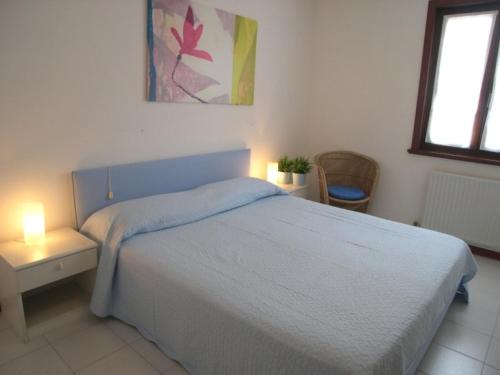 a bedroom with a bed with a blue headboard and two lamps at Villa Gradenigo in Grado