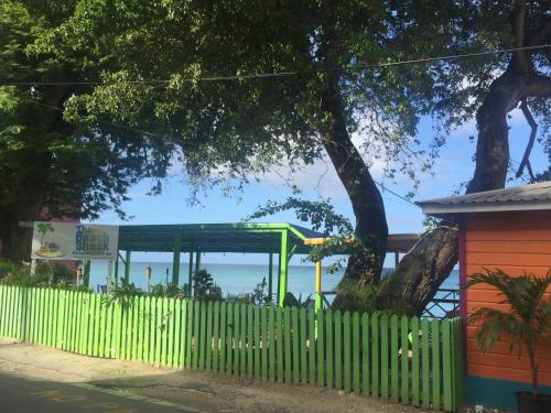 a playground behind a fence with the ocean in the background at Heywoods Villa in Saint Peter