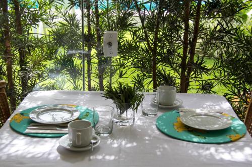 a table with a white table cloth with plates and cups at Casa Clara Paraty in Paraty