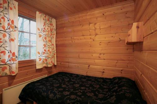 1 dormitorio con 1 cama en una habitación de madera en Koivula Cottages, en Jämsä