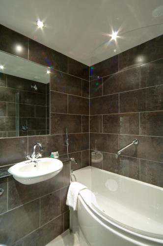 a bathroom with a sink and a tub and a toilet at Cedar Manor in Windermere