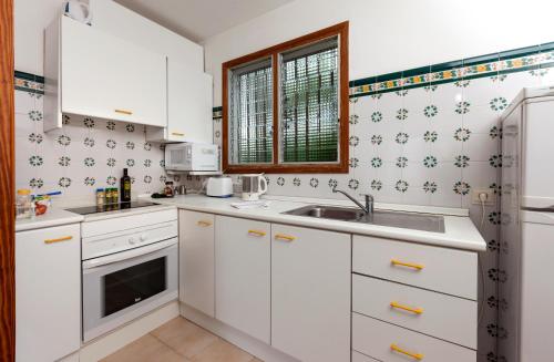 a kitchen with white cabinets and a sink at Apartamentos Leo in Port de Pollensa