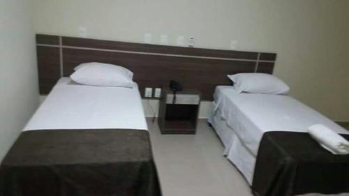 a hotel room with two beds and two nightstands at Apoema Hotel in Cuiabá