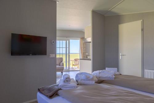 a bedroom with two beds and a television on a wall at Ostsee Mobilheime Heideby in Waabs