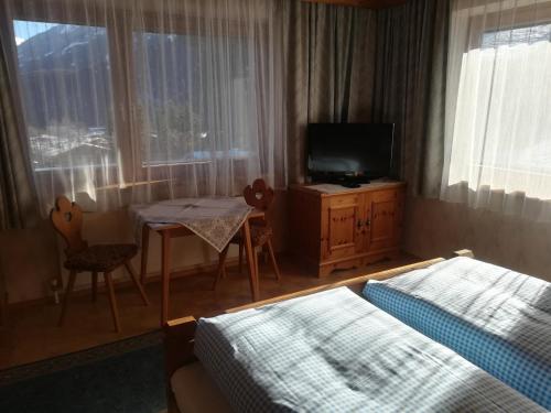 a bedroom with two beds and a table and a television at Waldrast in Finkenberg
