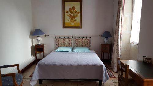 a bedroom with a bed with blue pillows on it at La Closeraie in Champagné-les-Marais