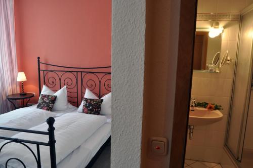 a bedroom with a bed and a bathroom with a sink at Hotel Grader in Neustadt an der Waldnaab