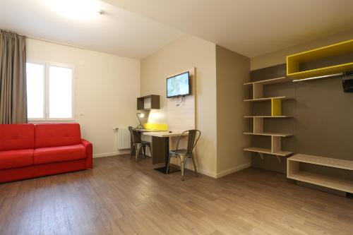 a living room with a red couch and a table at Westlodge Dardilly Lyon Nord in Dardilly