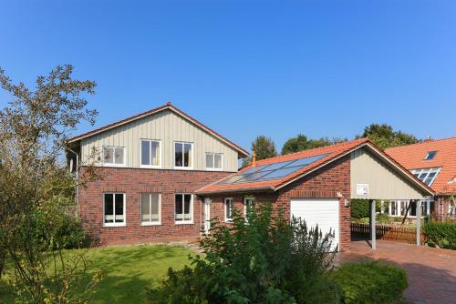 una casa de ladrillo con garaje en un patio en Ferienwohnungen im Haus Nordlichter, en Holtgast