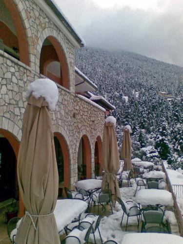 a group of chairs and umbrellas covered in snow at Vytina Mountain View Hotel in Vytina
