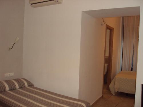 a bedroom with a bed in the corner of a room at Hostal Fenix in Jerez de la Frontera