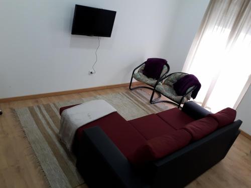 Una sala de estar con un sofá y un televisor de pantalla plana. en Casa do Centro, en Marinha Grande