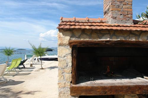 a stone fireplace on a beach with chairs and the water at Robinson Dora in Putniković