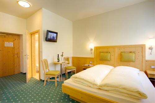 a bedroom with a bed and a table and chairs at Hotel Castel Latemar in Carezza al Lago