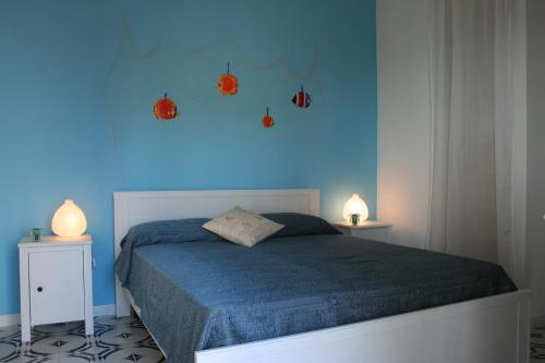 フォンターネ・ビアンケにあるVilla Mediterraneaのベッドルーム1室(青い壁のベッド1台、ランプ2つ付)