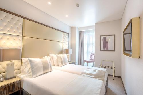 a hotel room with a large bed and a chair at Hotel MeraPrime Gold Lisboa in Lisbon