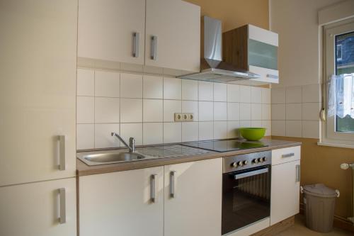 una pequeña cocina con armarios blancos y fregadero en Apartment Widey Str. 52, en Witten