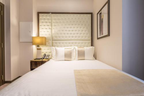 a bedroom with a large white bed and a lamp at Hotel MeraPrime Gold Lisboa in Lisbon