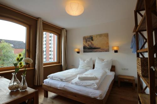 una camera da letto con un letto con lenzuola bianche e una finestra di Ferienhaus Lüneburg a Lüneburg