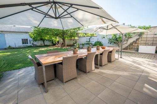 a patio with a wooden table and two umbrellas at SCHEIBER Wein & Gästehaus in Weiden am See