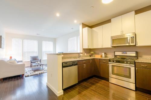 a kitchen with wooden floors and white cabinets at Sage Apartments Boston Logan Airport Chelsea in Chelsea