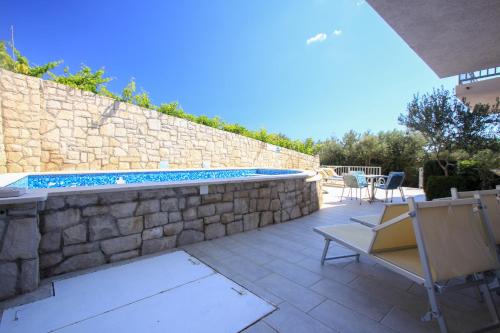 a patio with a pool and chairs next to a stone wall at Apartments Marketa in Gornji Dingač