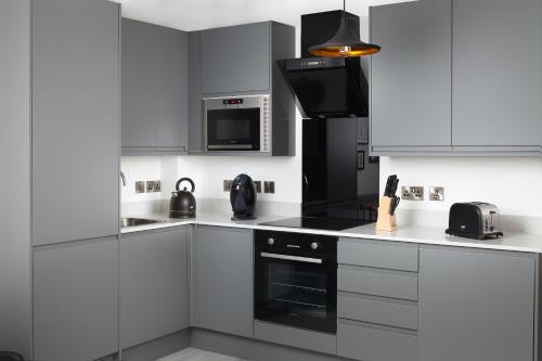 cocina con armarios blancos y fogones negros en We Love HU, en Hull