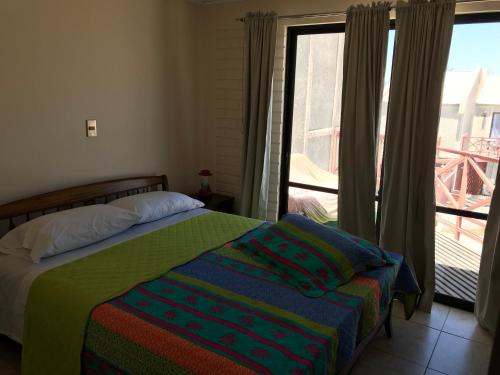 a bedroom with a bed and a window with a balcony at Bahia Inglesa Apartamentos in Bahia Inglesa