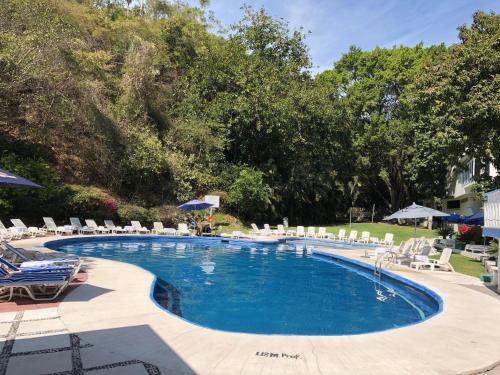 a large swimming pool with chairs and umbrellas at Villa Bejar Tequesquitengo in Tequesquitengo