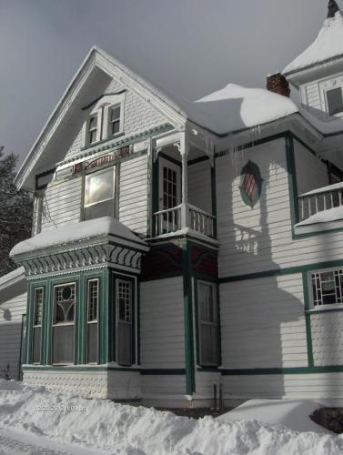 a white house with green trim in the snow at Antique Rose Inn Windham in Windham